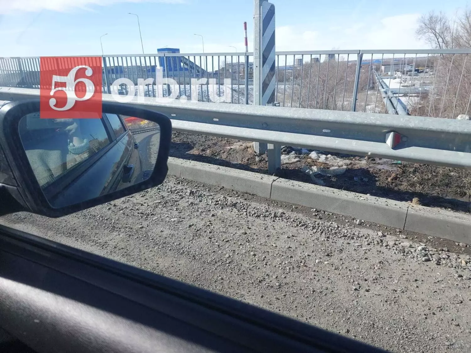 На мосту на улице Конституции СССР каменная отсыпка лежит прямо на дороге